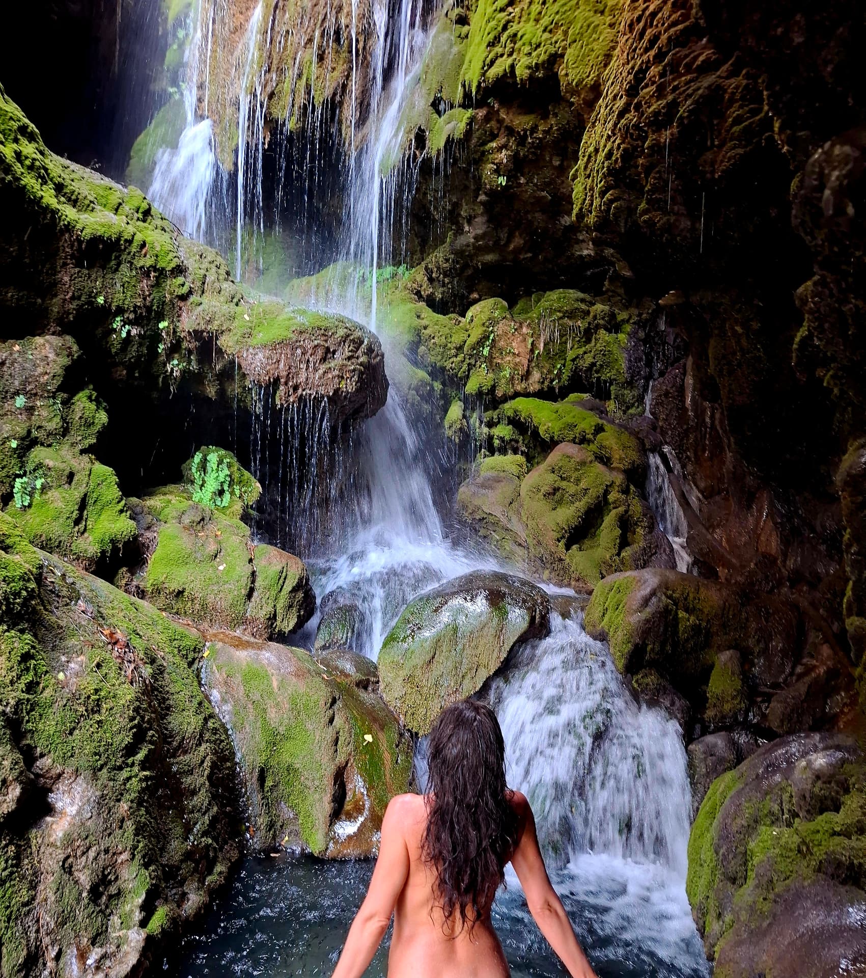 Woman at a mossy waterfall